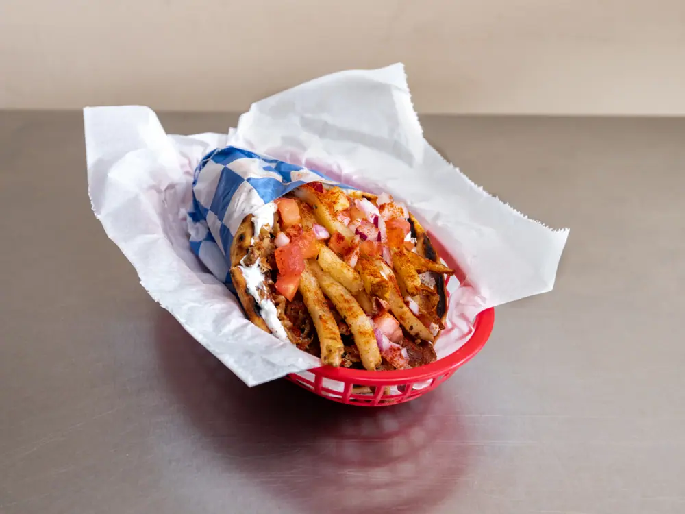 Traditional pork gyro with fries, tomato and onion in pita