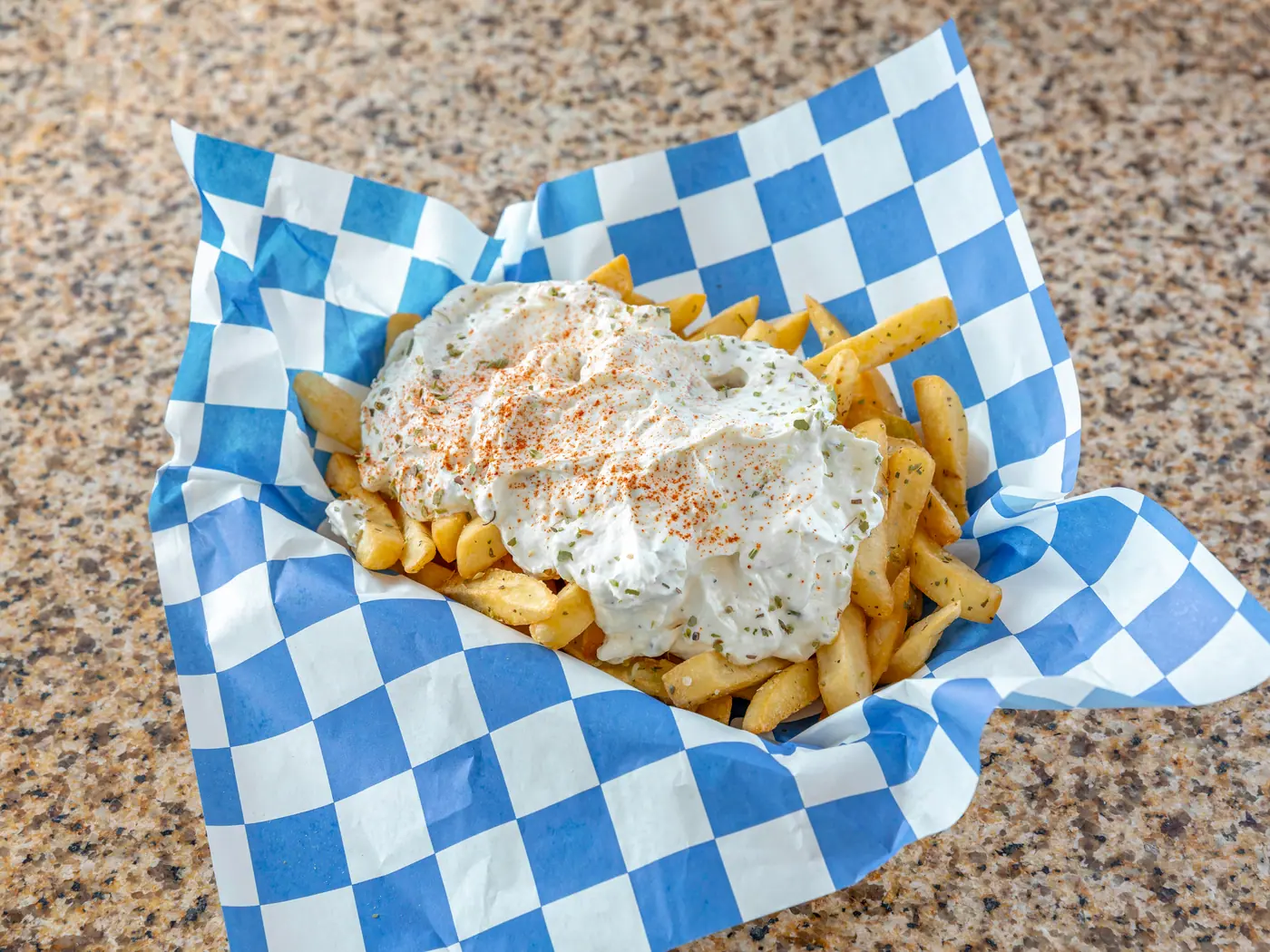 Seasoned fries topped with tzatziki